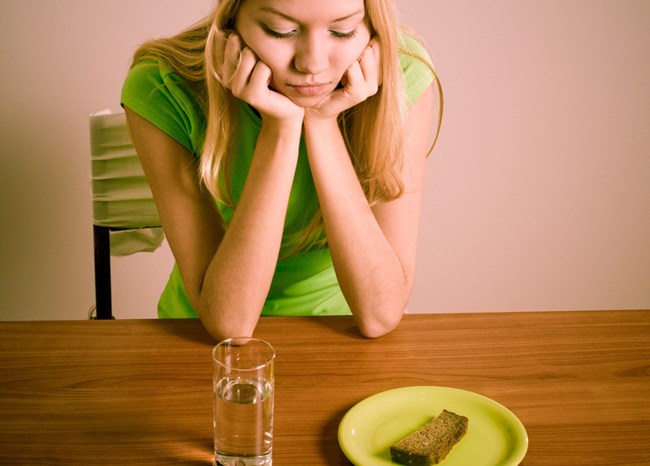 Une fille est assise devant un verre d'eau et du pain